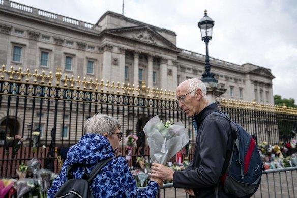 A couple lay flowers outside Buckingham Palace on September 9, 2022 in London.