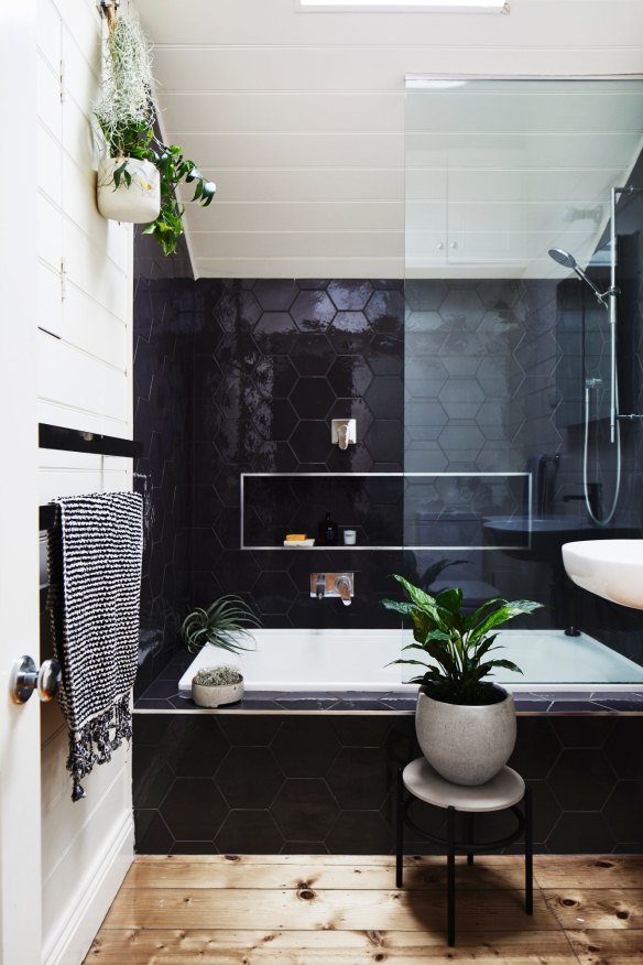 A skylight floods the monochromatic upstairs bathroom. The plant stand and hanging basket were designed by Jacqui and business partner Alana Langan for Ivy Muse.