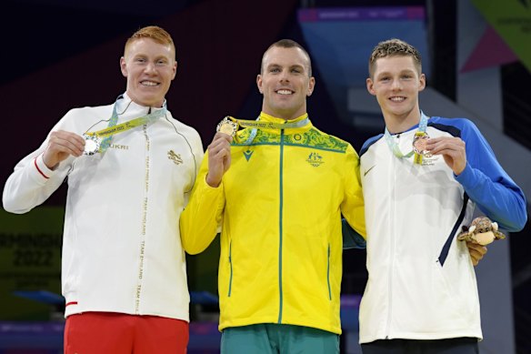 Silver medalist Tom Dean of England, gold medalist Kyle Chalmers of Australia and bronze medalist Duncan Scott of Scotland, from left to right, pose with their medals on the podium of the Men's 100 meters freestyle final.
