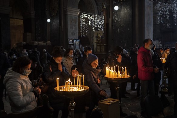 Christian worshippers light candles and pray after Sunday mass inside the Saints Peter and Paul Garrison Church in the city of Lviv.