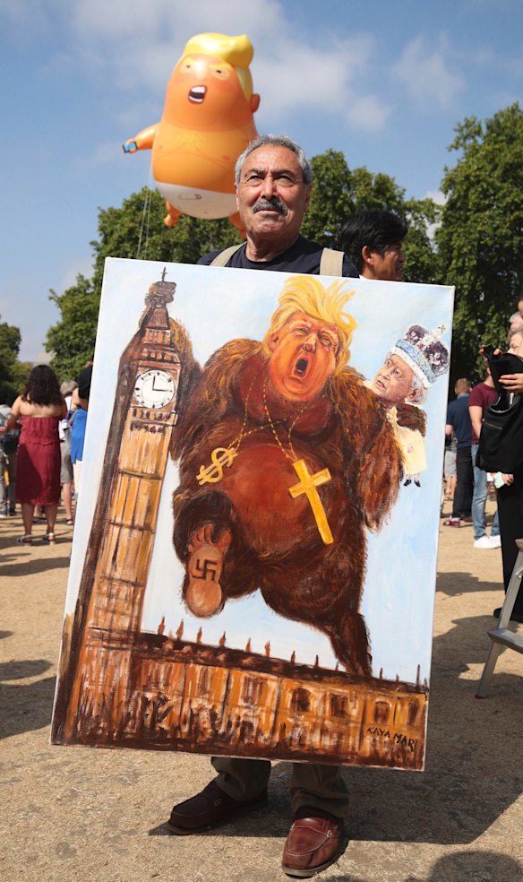 Political artist Kaya Mar holds a painting depicting a monstrous Donald Trump, during protests in London, Friday, July 13, 2018. 