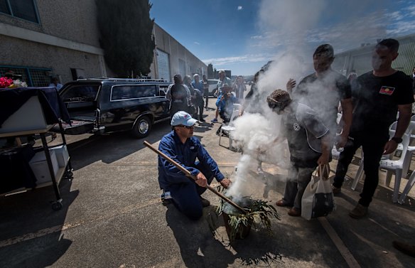Elders going through the smoke in a ceremony before the hearse's departure.