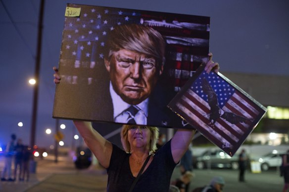 A President Donald Trump supporter holds up a painting of him outside of the Maricopa County Recorder's Office where votes in the general election are being counted in Phoenix. 