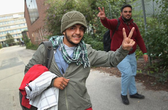 Migrants outside a makeshift registration center in Munich, Germany, gesture following their arrival by train earlier in the day from Hungary.