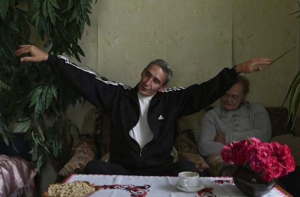 Boris Popov describes how he was tortured in a stress position by Russians, as his wife Natalia listens to his story in their home in Vorzel.