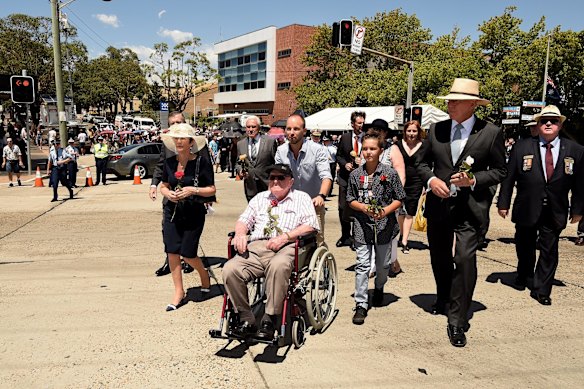 Crowds move to the bridge to throw roses onto the train tracks.