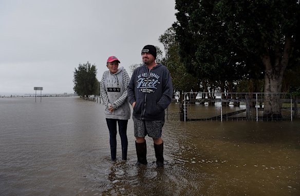 Amanda and Greg Soper walk through the floodwaters on their property near Shoalhaven Heads.