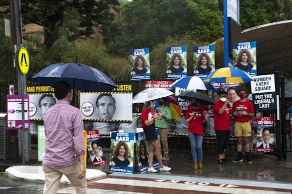 Political campaigners at Burwood Public School brave wet weather during the Strathfield byelection.