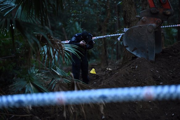 A NSW Police Forensic Services officer documents the crime scene where human remains have been unearthed.