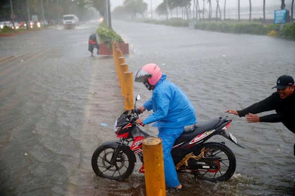 A motorist tries to avoid a flooded Manila street.