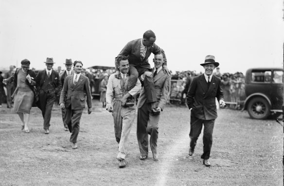 Aviator Captain Matthews being carried on the shoulders of two men after his arrival at Mascot on October 27, 1930.