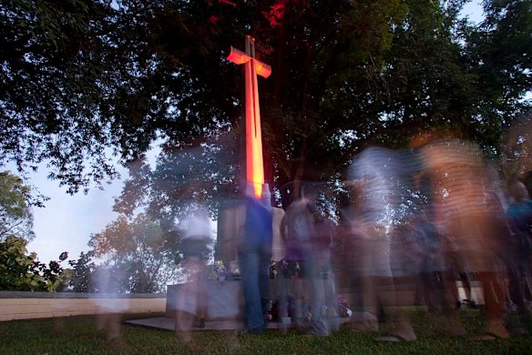People gather  around the cross of sacrifice after the Dawn Service at the Adelaide River War Cemetary 100 km south of Darwin.