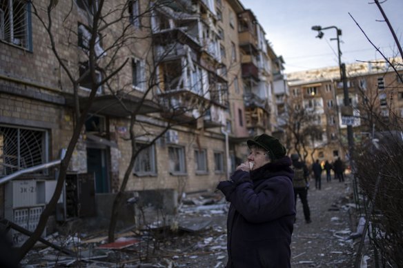 A woman looks at residential buildings damaged by a bomb in Kyiv.