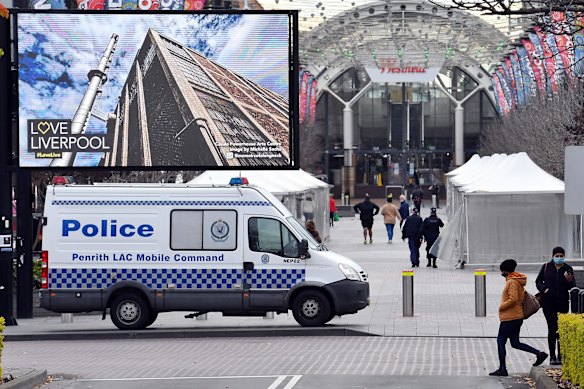 Shoppers walk past a NSW Police Mobile command unit parked at the Liverpool mall, as COVID restrictions tighten across Sydney.
