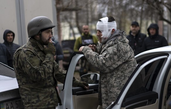 A wounded man talks to a soldier, left, after being evacuated from Irpin, on the outskirts of Kyiv.