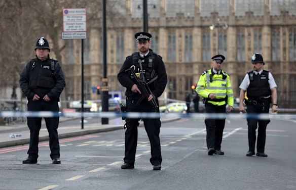 Armed officers attend to the scene outside Westminster Bridge and the Houses of Parliament.