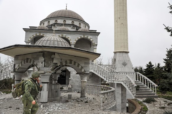 A Donetsk People's Republic trooper walks past a mosque damaged by Russian artillery.