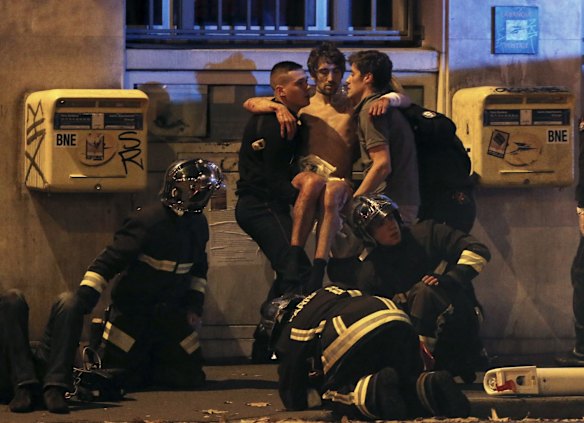 French fire brigade members aid an injured individual near the Bataclan concert hall. At least 30 people were killed in attacks in Paris and a hostage situation was under way at a concert hall in the French capital.