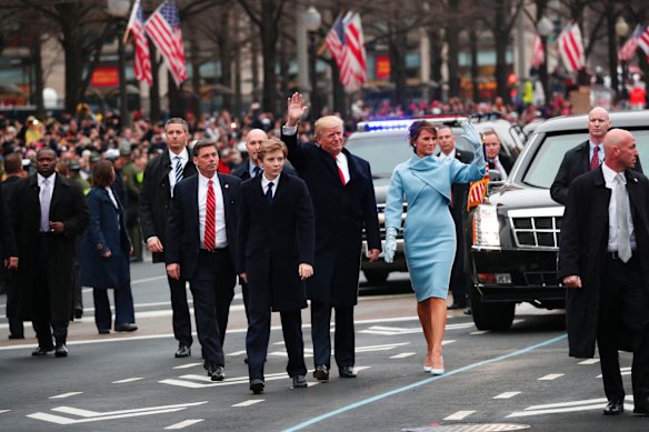 President Donald Trump and first lady Melania Trump walk briefly with their son Barron on the inauguration parade route in Washington.