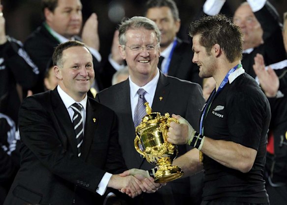 New Zealand Prime Minister John Key (L) shakes hands with All Blacks captain Richie McCaw (R) as International Rugby Board (IRB) Chairman Bernard Lapasset looks on.