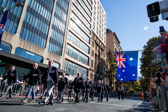 Spectators watch the ANZAC Day march down Elizabeth St, Sydney.