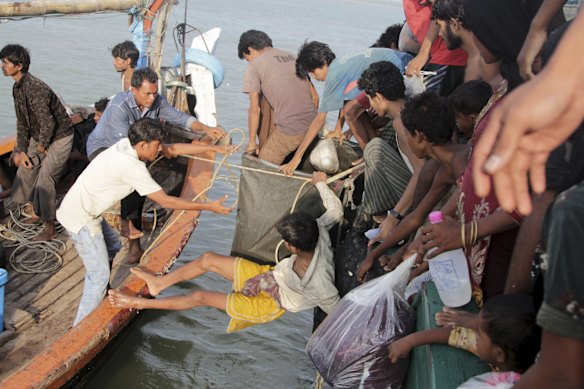 Acehnese fishermen help migrants to transfer to their boat on the sea off East Aceh, Indonesia, Wednesday, May 20, 2015. Hundreds of migrants stranded at sea for months were rescued and taken to Indonesia, officials said Wednesday, the latest in a stream of Rohingya and Bangladeshi migrants to reach shore in a growing crisis confronting Southeast Asia. 