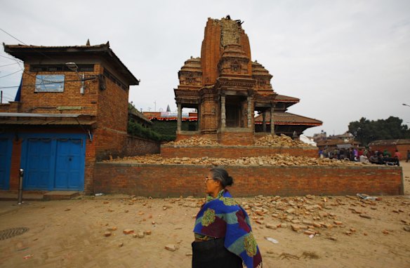 A Nepalese woman walks past a collapsed temple in Bhaktapur Durbar Square after an earthquake in Kathmandu, Nepal, Sunday, April 26, 2015 