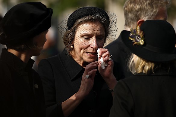 BALLATER, ABERDEENSHIRE - SEPTEMBER 11: A woman looks emotional as people gather in tribute as the cortege carrying the coffin of the late Queen Elizabeth II passes by on September 11, 2022 in Ballater, United Kingdom. Elizabeth Alexandra Mary Windsor was born in Bruton Street, Mayfair, London on 21 April 1926. She married Prince Philip in 1947 and ascended the throne of the United Kingdom and Commonwealth on 6 February 1952 after the death of her Father, King George VI. Queen Elizabeth II died at Balmoral Castle in Scotland on September 8, 2022, and is succeeded by her eldest son, King Charles III.  (Photo by Jeff J Mitchell/Getty Images) .