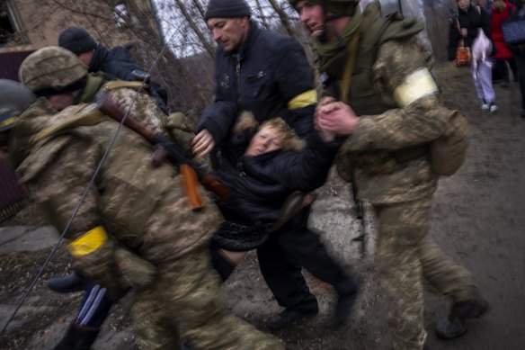 A sick woman is carried in semi-conscious by Ukrainian soldiers as they cross the Irpin river as fleeing the city in the outskirts of Kyiv.