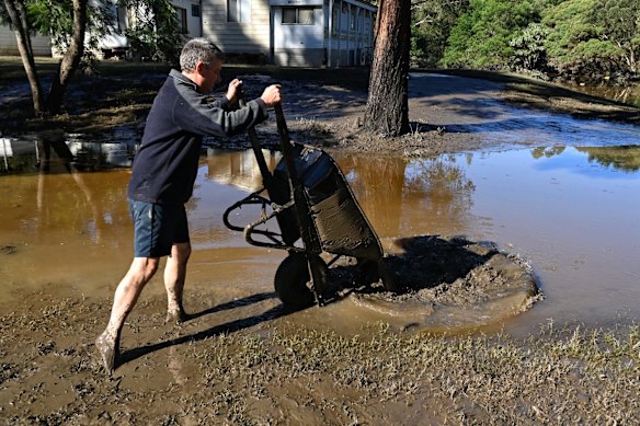 Russell Strickland clearing mud from their cabin at the Leetsvale Caravan Park on the Hawkesbury River.
