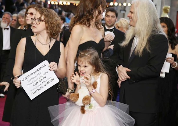 Sofia Miranda, daughter of Chilean Best Cinematography nominee Claudio Miranda for the film "Life of Pi," makes a face as she walks the red carpet with her father Claudio (R) and her mother Kelli Bean Miranda (C) at the 85th Academy Awards.