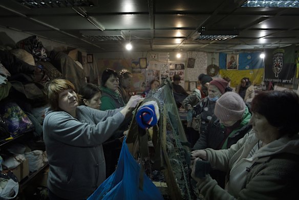 A group of women from Uman tie strips of donated material creating camouflage nets in a community shelter in Uman. The nets are used at checkpoints and strategic positions by the Ukrainian military, police and civil defence.