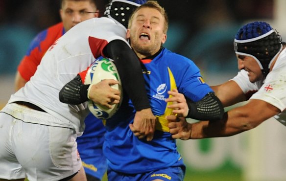 Romania's Florin Surugiu (C) is tackled by Georgia's Ilia Zedginidze (L) and David Khinchagishvili.