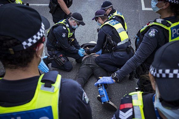 An anti-lockdown protester is arrested by Victoria Police officers during the rally.