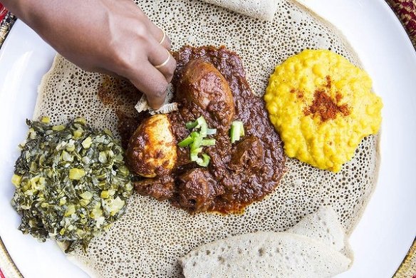 Sauteed silverbeet, slow-cooked chicken curry and turmeric-yellow split peas on injera at Saba's in Fitzroy. 
