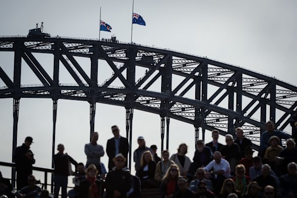 Flags fly at half mast on the Harbour Bridge as people gather on the steps of the Opera House for the memorial service of former Prime Minister Bob Hawke. 