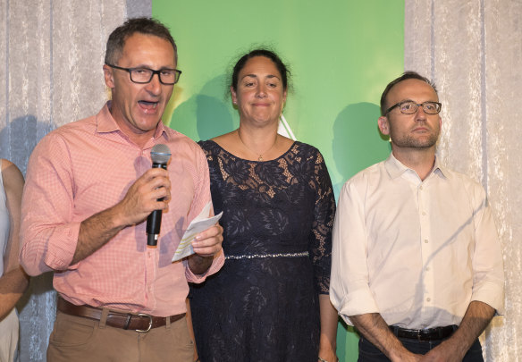 Standing with candidate Alex Bhathal and deputy leader Adam Bandt, Greens leader Richard Di Natale concedes defeat in Batman on Saturday, 