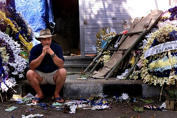 Mr David Stewart sits amongst the wreaths that line Legian St, Kuta, at the entrance to the Southern end of the 12 October Legian St bomb site, after visiting where the Sari Club once stood.