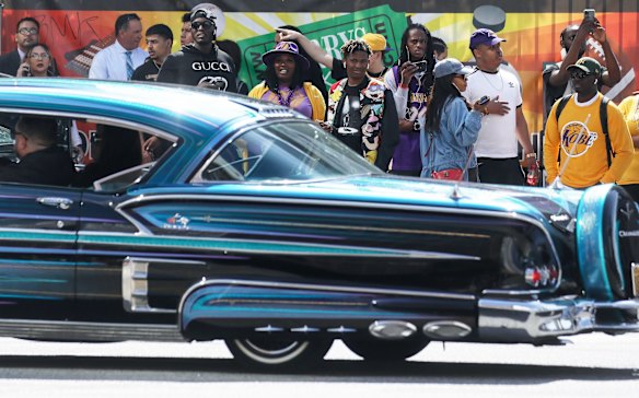 A lowrider passes fans standing outside the Celebration of Life for Kobe and Gianna Bryant memorial service at Staples Center.