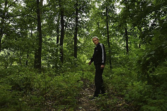 Boris Popov points to a wooden stake that marks the grave of a colonel in a landmined forest near their home in Vorzel. It was in this forest that Boris witnessed the colonel being tortured and killed. 