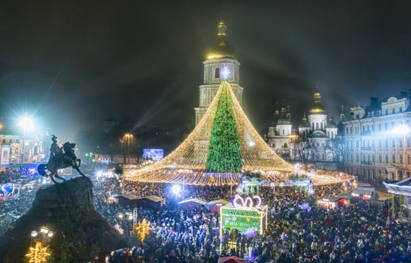 Crowds of people celebrate the New Year around the Christmas tree with the St. Sofia Cathedral in the background in Kyiv, Ukraine.