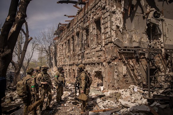 Ukrainian troops on patrol outside a ruined shopping centre destroyed by a Russian missile attack in Kharkiv.