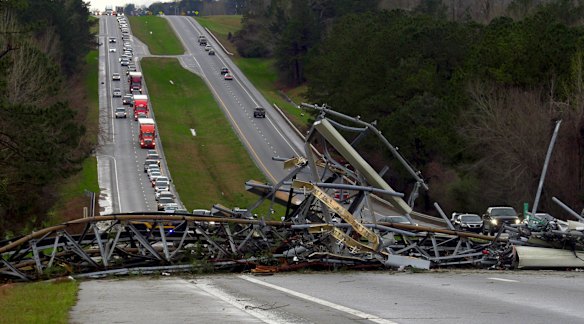 A fallen telephone tower lies across US Route 280 highway in Lee County, Alabama after a tornado struck on  Sunday.