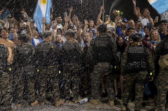 Soccer fans spray foam as they watch the bus taking the Argentine soccer team that won the World Cup to the Argentina Soccer Association grounds where they will spend the night after landing at Ezeiza airport on the outskirts of Buenos Aires, Argentina.