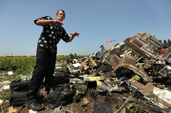 Donetsk People's Republic sniper Eugene Lukovkin aged 30 stands amongst the pilots bags at one of the sites where he witnessed the front section of Malaysian flight MH17 crashing and found the pilots bodies, on the outskirts of Rassypnoe village in the self proclaimed Donetsk People's Republic, Ukraine. 26th July, 2014. Photo: Kate Geraghty