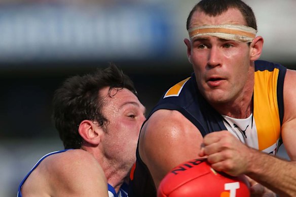 Shannon Hurn handballs while being tackled by Todd Goldstein.