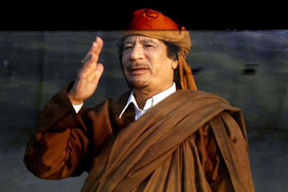 Libyan leader Moamer Kadhafi gestures at supporters while standing behind bulletproof glass during a ceremony marking the birth of Islam's Prophet Mohammed in Tripoli on February 13.