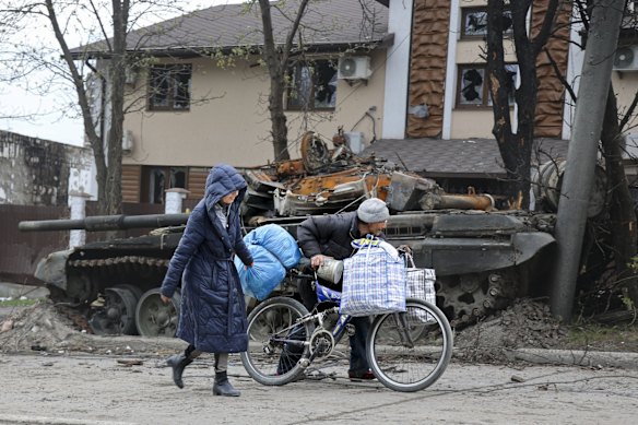 Local civilians walk past a tank destroyed during heavy fighting in an area controlled by Russian-backed separatist forces in Mariupol. Taking Mariupol would deprive Ukraine of a vital port and complete a land bridge between Russia and the Crimean Peninsula, seized from Ukraine from 2014.