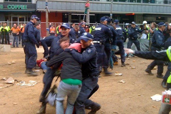 Police wrestle with protesters while trying to clear the makeshift camp.