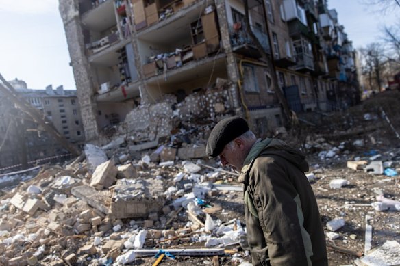 A man walks amid debris in front of a residential apartment complex that was heavily damaged by a Russian attack in Kyiv.